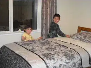 ホームステイのゲストルームにおかれたキングベッドとそのわきに立っている子供たち