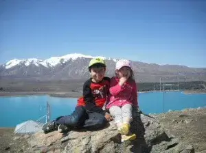 テカポ湖と雪山のコントラストが背景にマウントジョンの頂上にいる男の子と女の子 雪山とテカポ湖の色のコントラストが最高