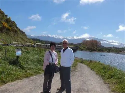 カイコウラへ行く途中の山をバックに立つシニアのご夫婦