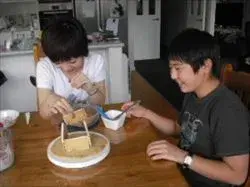 ホームステイゲスト達と一緒にクリスマスのおかしの家づくりをしている