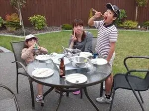 ホームステイゲストと子どもたち２人がお庭のテーブルでディナーを楽しんでいる様子