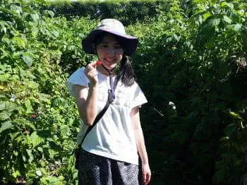 ラズベリーピッキングをしている女性が取ったラズベリーを見せている