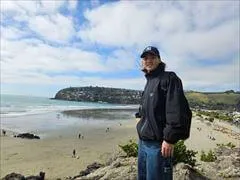 サムナビーチのビーチと砂浜をバックに洞窟の上に立っている男性、砂浜ビーチには人が歩いている